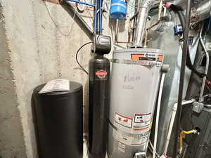 Utility room featuring water softener and strapped water heater