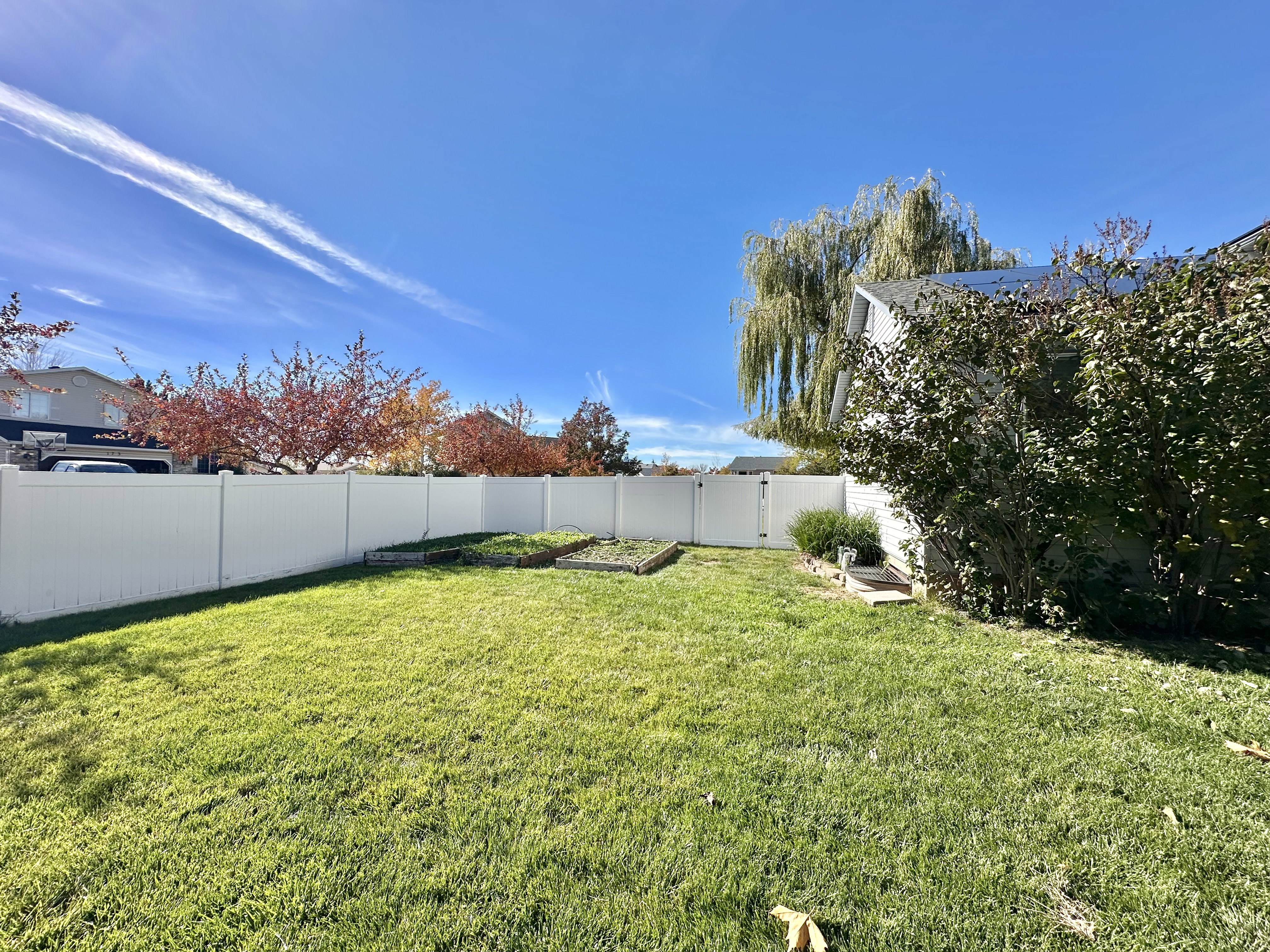 Fenced backyard with GATE near garden boxes.