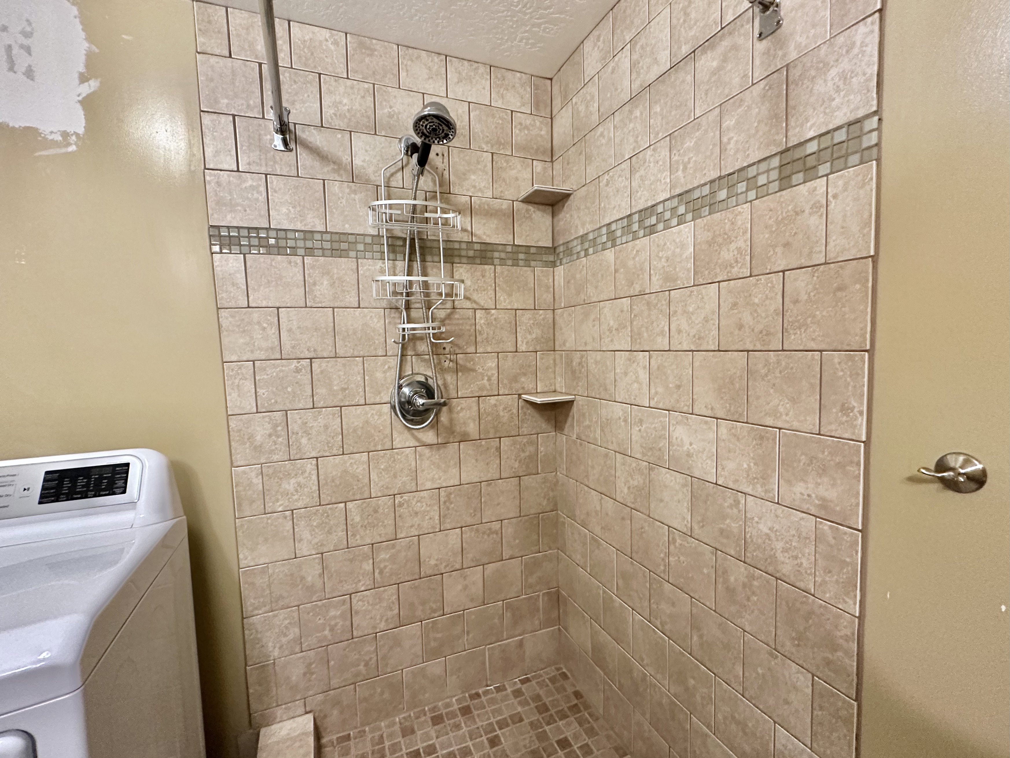 Bathroom featuring washer / clothes dryer and a tile shower