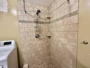 Bathroom featuring washer / clothes dryer and a tile shower