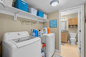 Laundry area featuring a textured ceiling, independent washer and dryer, and light tile patterned floors