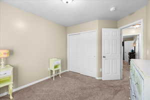 Bedroom featuring light colored carpet, a closet, and a textured ceiling