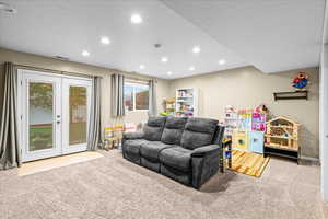 Living area featuring a textured ceiling, light carpet, french doors, and recessed lighting