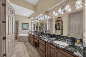 Bathroom featuring a spacious closet, double vanity, a garden tub, light tile patterned floors, and a stall shower
