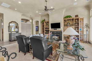 Living room featuring recessed lighting, light tile patterned floors, ceiling fan, a fireplace, and arched walkways