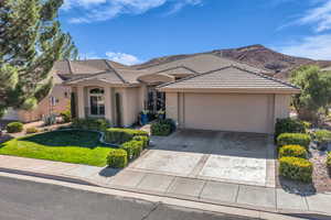 View of front facade with driveway, a front lawn, stucco siding, and an attached garage