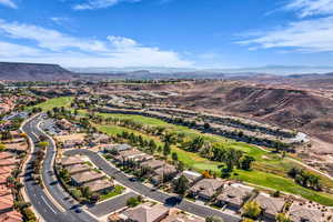 Aerial view of property and surrounding area featuring a mountain backdrop, a golf club, and nearby suburban area