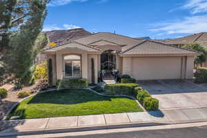 View of front of property featuring a garage, concrete driveway, stucco siding, a front lawn, and a tiled roof