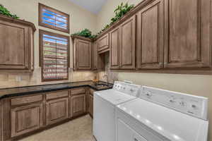 Laundry area with separate washer and dryer, cabinet space, and light tile patterned floors