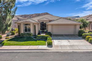 View of front of home featuring driveway, stucco siding, a garage, and a front yard
