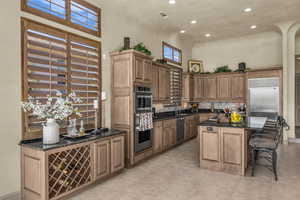 Kitchen with dark stone countertops, a breakfast bar area, decorative backsplash, a center island, and recessed lighting