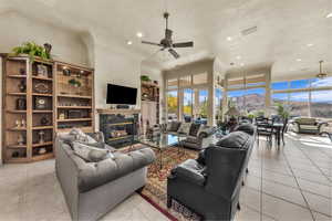 Living room featuring a ceiling fan, recessed lighting, light tile patterned flooring, and a fireplace