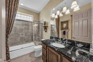 Full bath with bath / shower combo with glass door, vanity, light tile patterned floors, and a chandelier