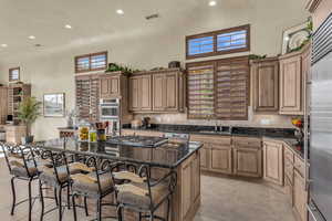 Kitchen featuring recessed lighting, dark stone countertops, decorative backsplash, a kitchen island, and a kitchen breakfast bar
