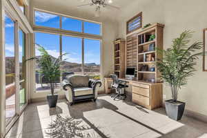 Tiled office with ceiling fan and a towering ceiling