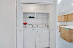 Washroom featuring washing machine and clothes dryer, light colored carpet, and recessed lighting