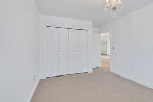 Unfurnished bedroom with carpet, a chandelier, and a closet