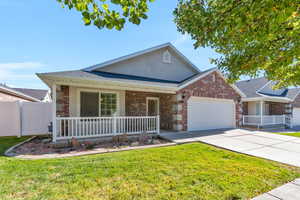 Single story home featuring a porch, roof with shingles, driveway, brick siding, and a garage