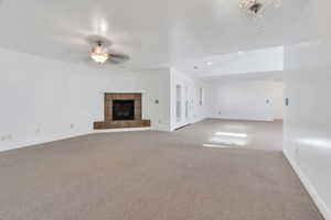Unfurnished living room with carpet flooring, a tiled fireplace, a ceiling fan, recessed lighting, and vaulted ceiling