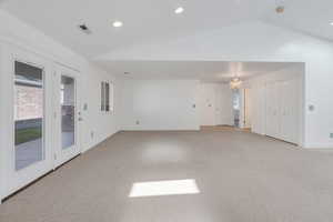 Spare room with light carpet, vaulted ceiling, a chandelier, and recessed lighting
