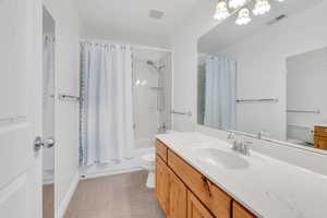 Bathroom with vanity, shower / bathtub combination with curtain, light carpet, and a chandelier