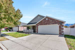 Ranch-style house with concrete driveway, a porch, brick siding, an attached garage, and a mountain view