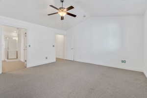 Unfurnished bedroom featuring lofted ceiling, light colored carpet, ceiling fan, and ensuite bathroom