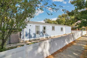 Manufactured / mobile home with a fenced front yard and roof with shingles