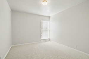 Carpeted empty room featuring baseboards