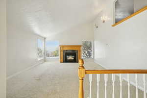 Unfurnished living room with carpet floors, high vaulted ceiling, and a fireplace