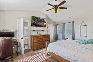 Bedroom featuring lofted ceiling, carpet floors, an office area, ensuite bath, and a ceiling fan