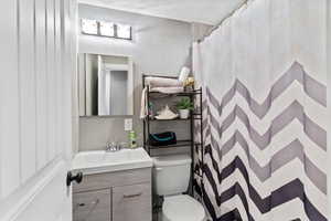 Bathroom featuring curtained shower, vanity, and a textured ceiling