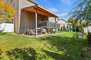 Rear view of house with a fenced backyard, a wooden deck, and a playground
