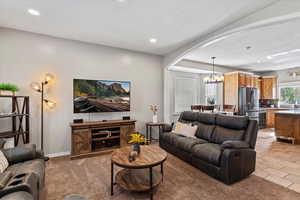 Living room with a chandelier, arched walkways, light carpet, and recessed lighting