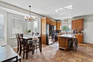 Kitchen featuring brown cabinetry, stainless steel appliances, a kitchen breakfast bar, a kitchen island, and recessed lighting