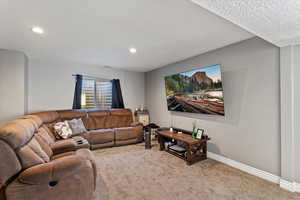 Carpeted living area featuring a textured ceiling and recessed lighting