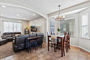 Dining room with arched walkways, recessed lighting, and a chandelier