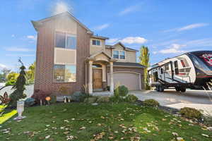 View of front of home with brick siding, a front lawn, concrete driveway, an attached garage, and stucco siding