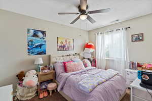 Carpeted bedroom featuring a textured ceiling and ceiling fan