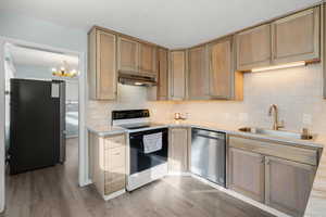 Kitchen featuring appliances with stainless steel finishes, light wood-style floors, backsplash, and under cabinet range hood