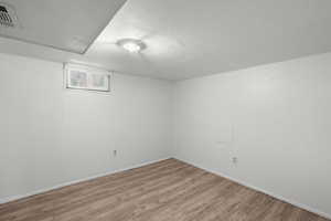 Below grade area with light wood-type flooring and a textured ceiling