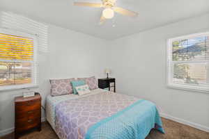 Bedroom with dark colored carpet and a ceiling fan