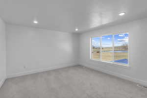 Carpeted empty room with a water view and recessed lighting