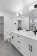 Bathroom with a marble finish shower, double vanity, and a spacious closet