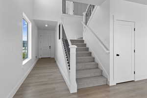 Stairway with wood finished floors and a towering ceiling