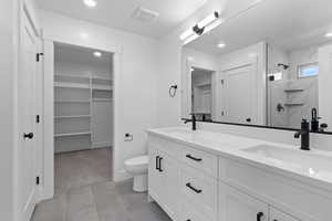 Full bathroom with a spacious closet, double vanity, a marble finish shower, recessed lighting, and light carpet
