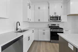 Kitchen with appliances with stainless steel finishes, white cabinets, and light stone counters