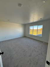 Carpeted empty room with baseboards and a textured ceiling
