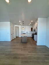 Kitchen featuring open floor plan, a kitchen island, recessed lighting, decorative light fixtures, and white cabinetry