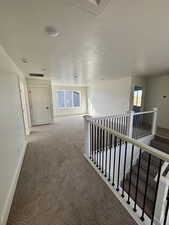 Hall with carpet, an upstairs landing, and a textured ceiling